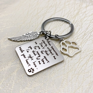 Polished pet memorial keychain with wing charm and paw print on white silk fabric