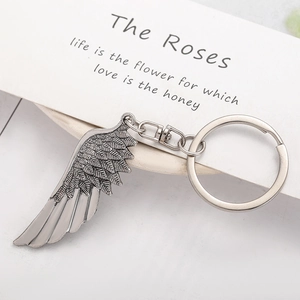 Detailed macro view of vintage silver angel wing keychain with intricate feather textures