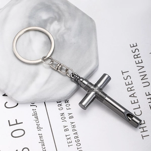 Macro shot of gun-black metal cross whistle keychain with intricate textured patterns