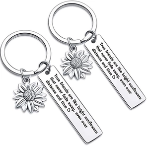 Polished stainless steel sunflower keychains with engraved True Friends quote on white base