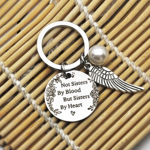 Macro detail of engraved heart sisterhood keychain with pearl and angel wing charm