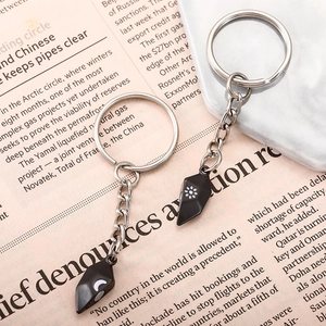 Detail view of magnetic sun and moon couple heart keychains on a white marble tray