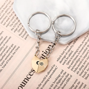Detail of couple's magnetic heart keychains with sun and moon icons on marble background