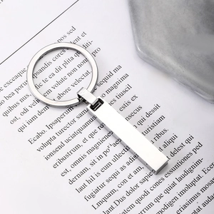 Détail d'un porte-clés minimaliste en acier inoxydable avec barre polie sur fond de marbre