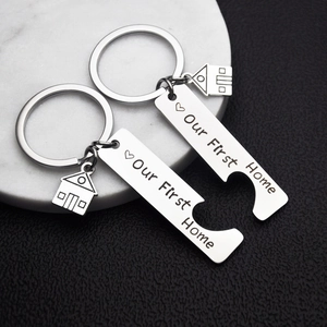 Detail of interlocking stainless steel house keychains with Our First Home engraving