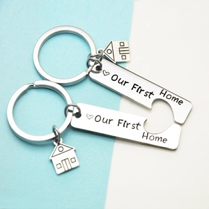 Macro shot of stainless steel keychain set with Our First Home engraving and house charm