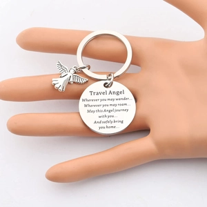 Porte-clés Travel Angel argenté avec pendentif ange et charme gravé sur un modèle de main