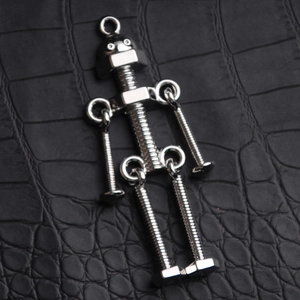 Close-up of industrial screw robot keychain with movable limbs on black leather background
