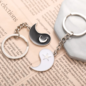 Matching sun and moon tai chi couples keychain set on a gray marble background
