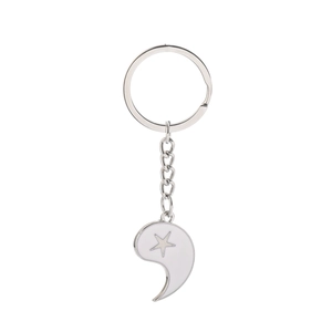 Close-up of white enamel Tai Chi half-pendant keychain with a silver star detail