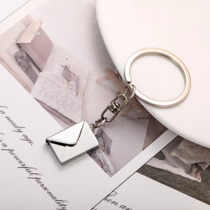 Polished silver envelope keychain with pull-out card on minimalist magazine background