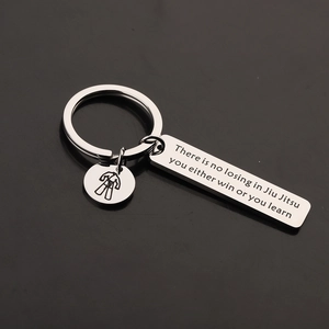 Stainless steel Jiu Jitsu keychain with motivational quote and gi icon on dark background