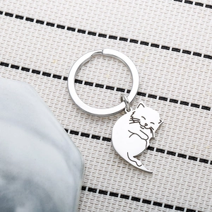 Macro shot of cute cartoon cat keychain with silver metal ring on woven texture surface