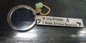 Macro view of stainless steel dog groomer keychain with heart charm and engraved tool icons