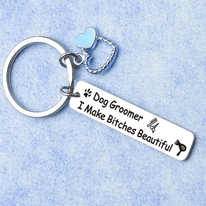 Detail of dog groomer keychain with heart charm and humorously engraved steel plate