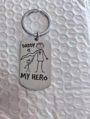 Detail view of stainless steel keychain with DADDY IS MY HERO engraved text and icon