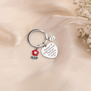 Detailed view of silver heart keychain with enamel flower on beige silk fabric