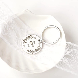Silver stainless steel Best Mom Ever keychain with floral wreath on a white shell plate