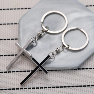 Detailed view of silver and black enamel cross keychains on a gray stone surface