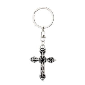 Detailed macro view of vintage gothic cross keychain with black stone and embossed patterns