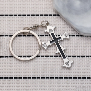 Vintage silver cross keychain with four crystals and floral scrollwork on woven background