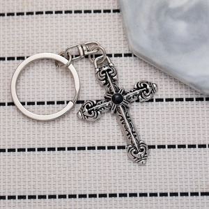 Close-up of gothic silver cross keychain with black gemstone and intricate carvings