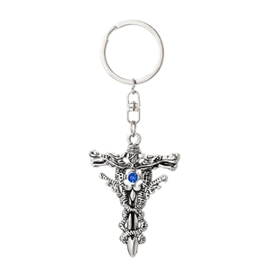 Macro view of vintage silver cross keychain with blue gemstone and twin snakes