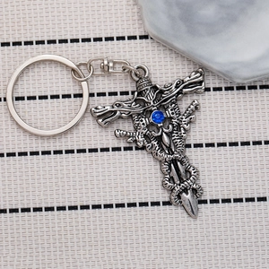Vintage sword and dragon cross keychain with a blue crystal on stone background
