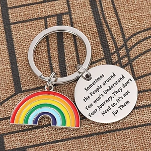 Rainbow stainless steel keychain with engraved inspirational quote charm on woven background