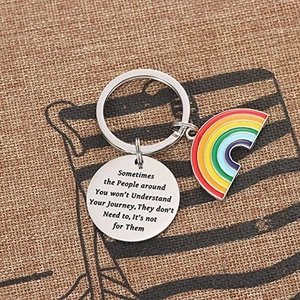 Rainbow stainless steel keychain with inspirational quote on textured linen background