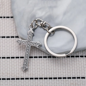 Sparkling rhinestone cross keychain with silver metal ring and lobster clasp on marble surface