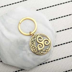 Golden stainless steel Celtic knot Triskelion keychain on white stone marble base