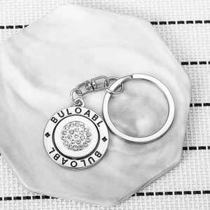 Close-up of rotatable silver metal keychain with sparkling crystal rhinestones and engraving