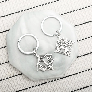 Genshin Impact stainless steel keychains with intricate fantasy symbols on marble tray