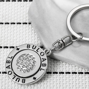 Rotating round metal keychain with sparkling crystals and engraved lettering details