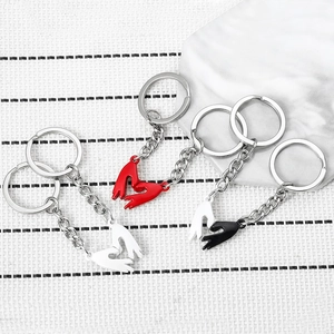 Detail view of magnetic heart-shaped hand-holding keychain set in red, white and black