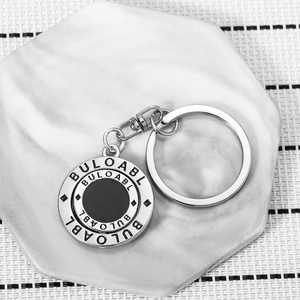 Rotating silver metal keychain with BULOABL engraving on white marble display base