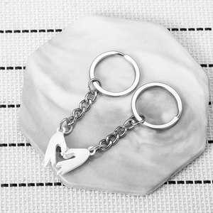 Magnetic heart gesture couple keychain with white hand pendants on marble display