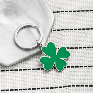 Creative green four-leaf clover keychain with silver metal ring on marble tray