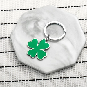 Exquisite green clover keychain with silver metal ring on marble textured background