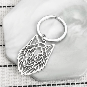 Détail du porte-clés tête de loup évidé en métal argenté poli sur marbre blanc