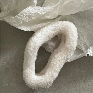 Close-up of white plush cloud hair claw clip with soft lamb wool texture on stone surface
