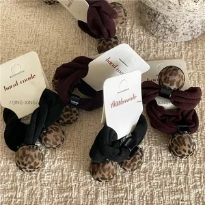 Detail of leopard print pom-pom hair ties in black and dark red on a display card