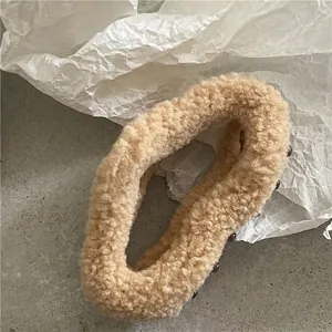 Close-up of soft camel plush hair claw clip with dark bead accents on marble texture