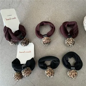Detail of leopard print pompom hair ties in red and black elastic fabric set