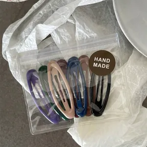 Set of 7 matte oval hair clips in assorted colors packed in a transparent handmade pouch