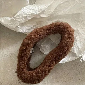 Detail shot of a plush dark brown scrunchie with soft lamb wool texture on a neutral surface