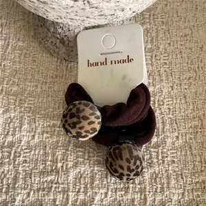 Detail of leopard print ball hair ties on a handmade card with a rustic background