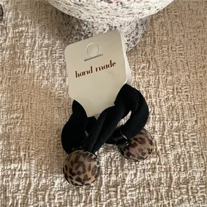 Detailed macro view of black elastic hair ties featuring cute leopard print pom pom charms