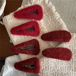 Set of 6 deep red plush velvet drop-shaped and oval hair clips on a woven background